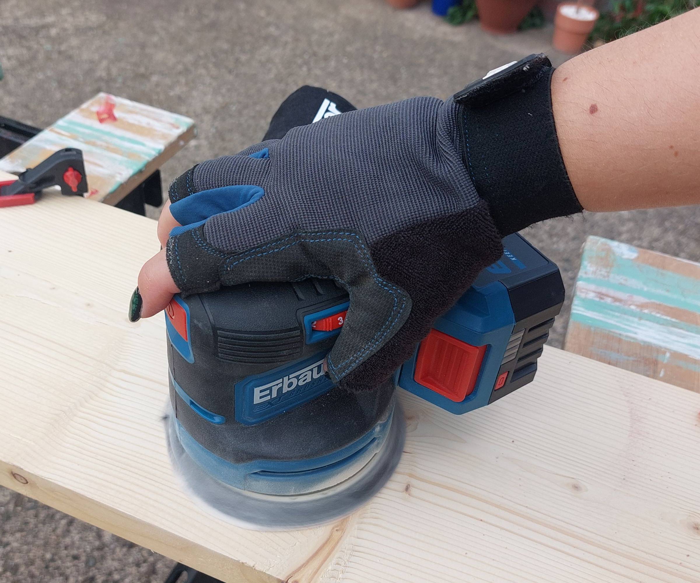 A sander tool being used to sand a piece of wood