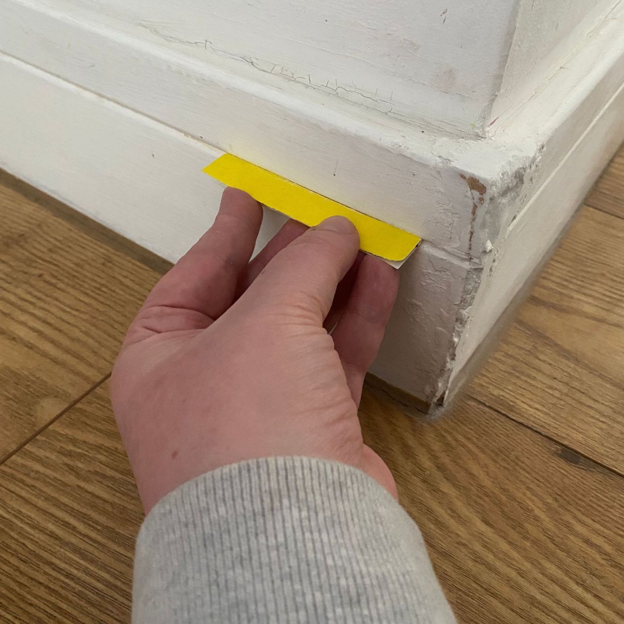 Using folded sandpaper to etch the existing skirting board groove into wood filler