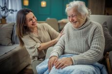 Portrait of an elderly mother and middle-aged daughter smiling together.