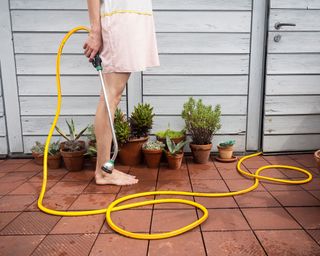 barefoot woman on deck with garden sprinkler