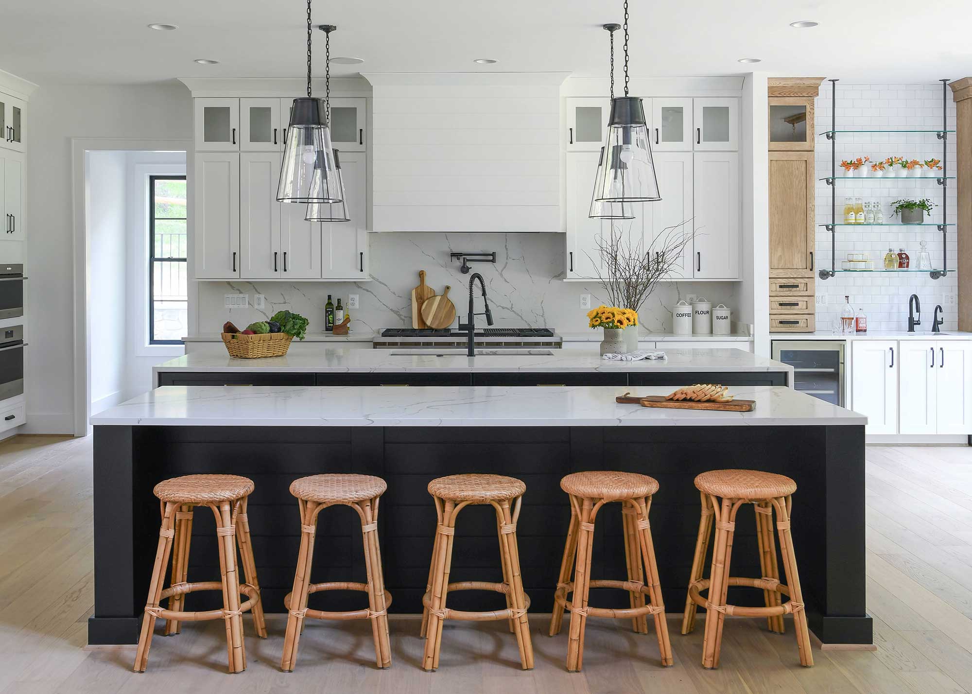 large blue kitchen island with wicker bar stools in white kitchen