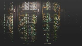 Data servers with colourful wires inside a meshed metal cupboard