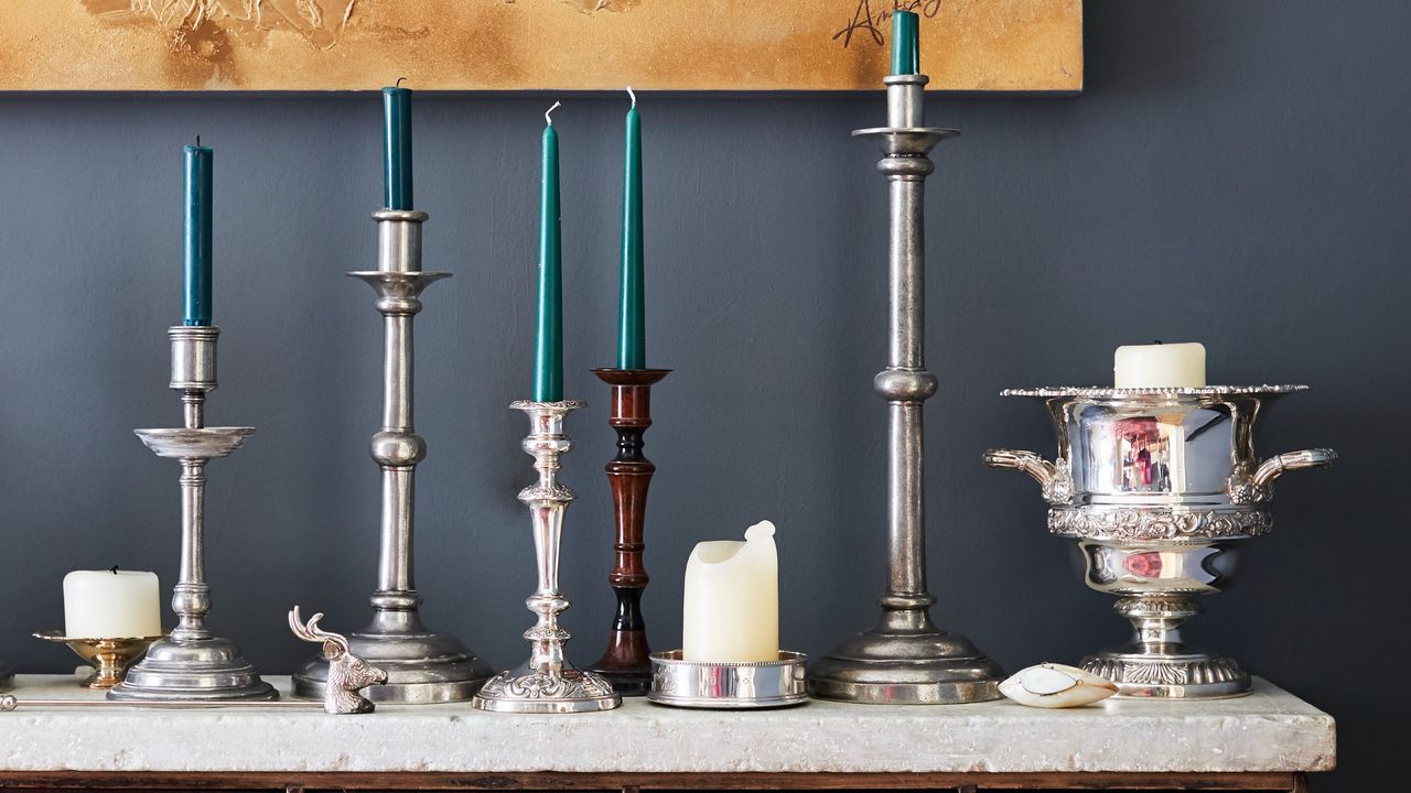 A line of candles and candlesticks on a sideboard