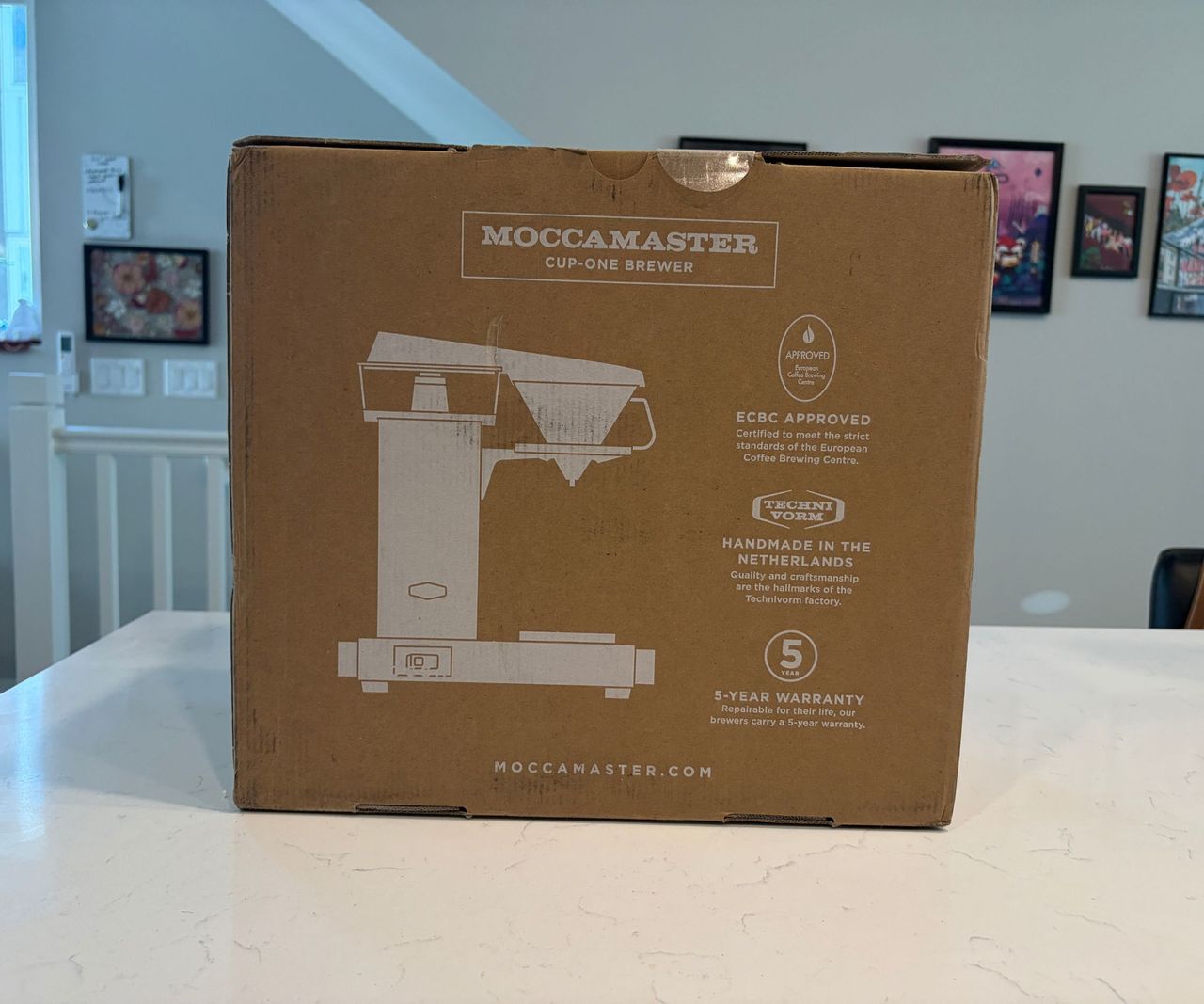 The Moccamaster Cup-One cardboard box on a white counter.