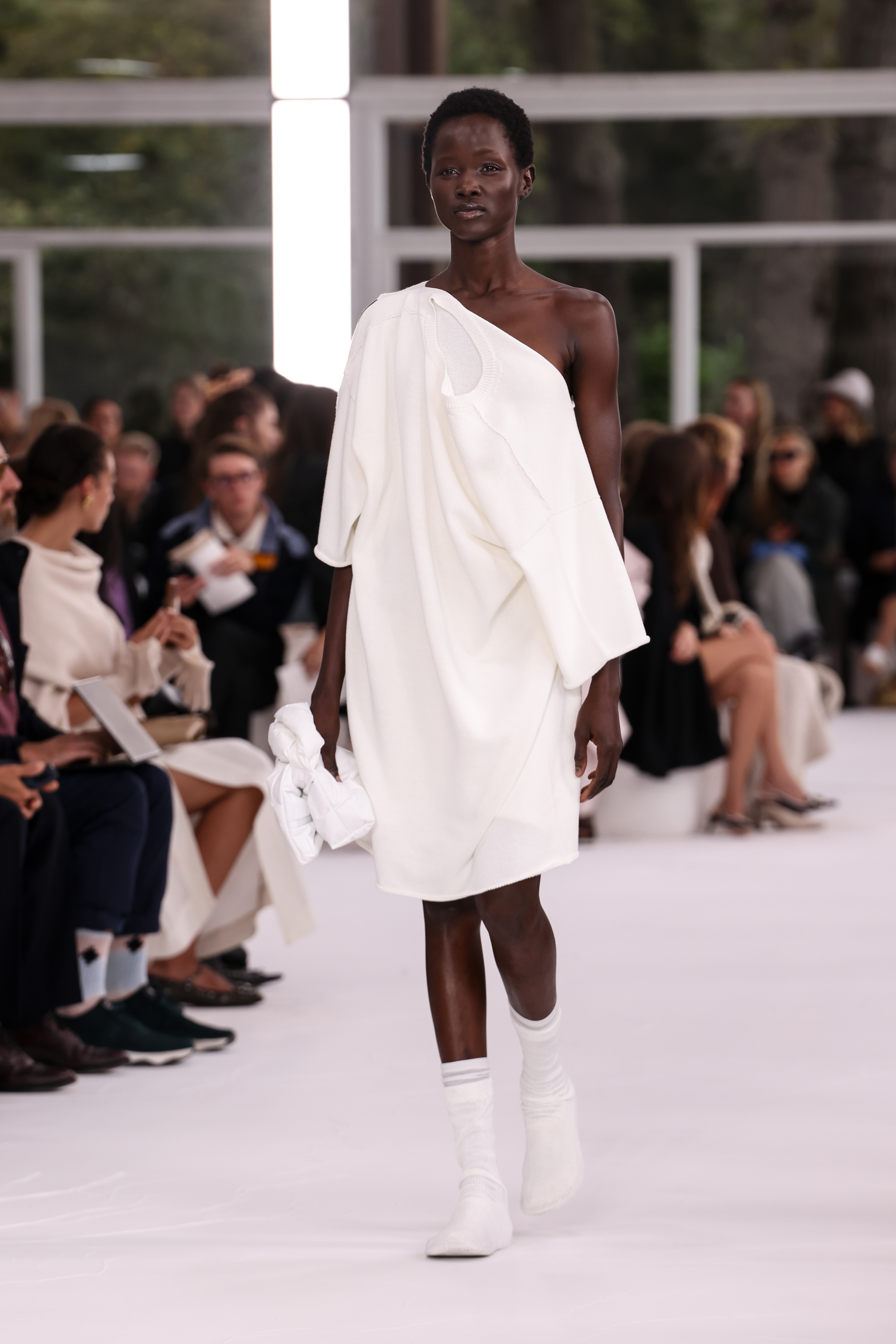 A woman wearing a white dress and white sock boots