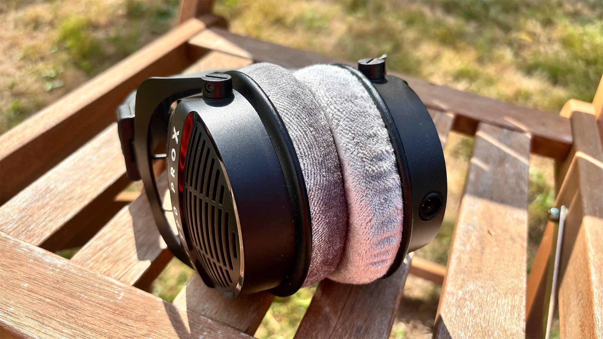 Beyerdynamic DT 990 Pro X wired headphones with earcups closed together on wooden garden chair