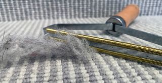 Grey and white striped carpet on stairs next to a ball of lint and pet hair to show how effective the carpet lint remover tool is