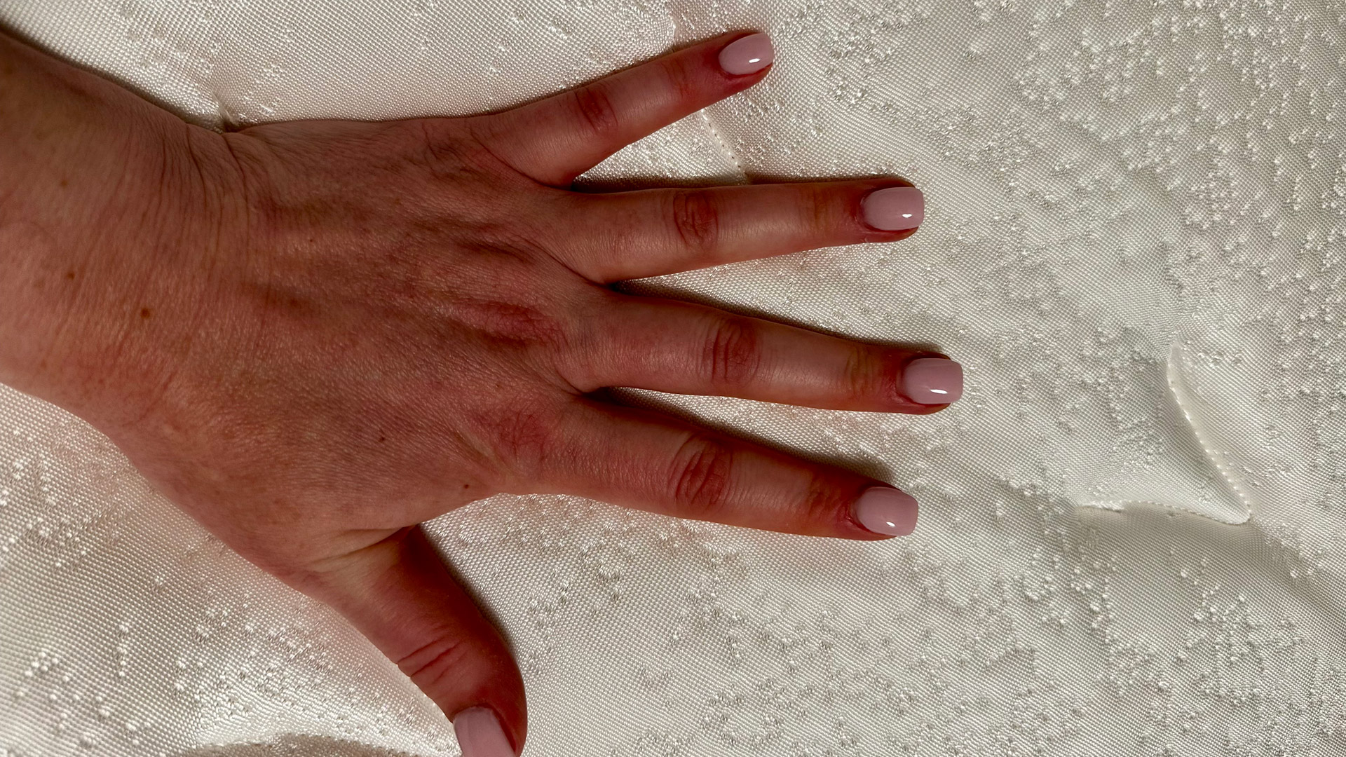 A hand pressing down on the Glacier Apex Hybrid mattress