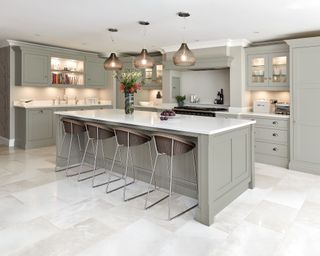 A kitchen with a large central island and glass cabinets with built-in lighting