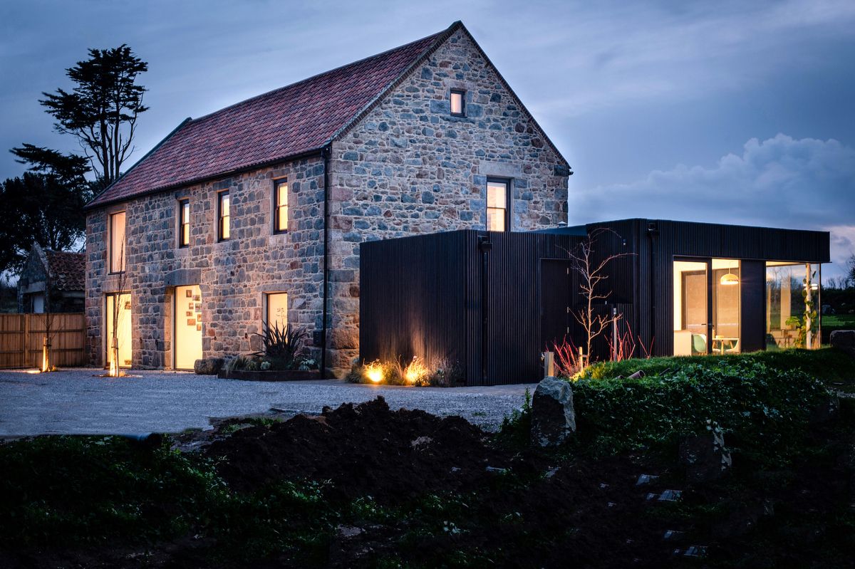 exterior of granite barn conversion and black timber clad extension