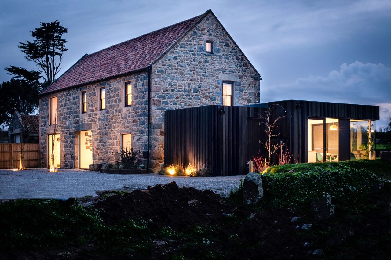 exterior of granite barn conversion and black timber clad extension