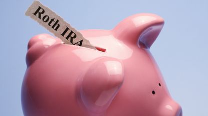 A piggy bank has a strip of paper coming out of its slot that says Roth IRA.