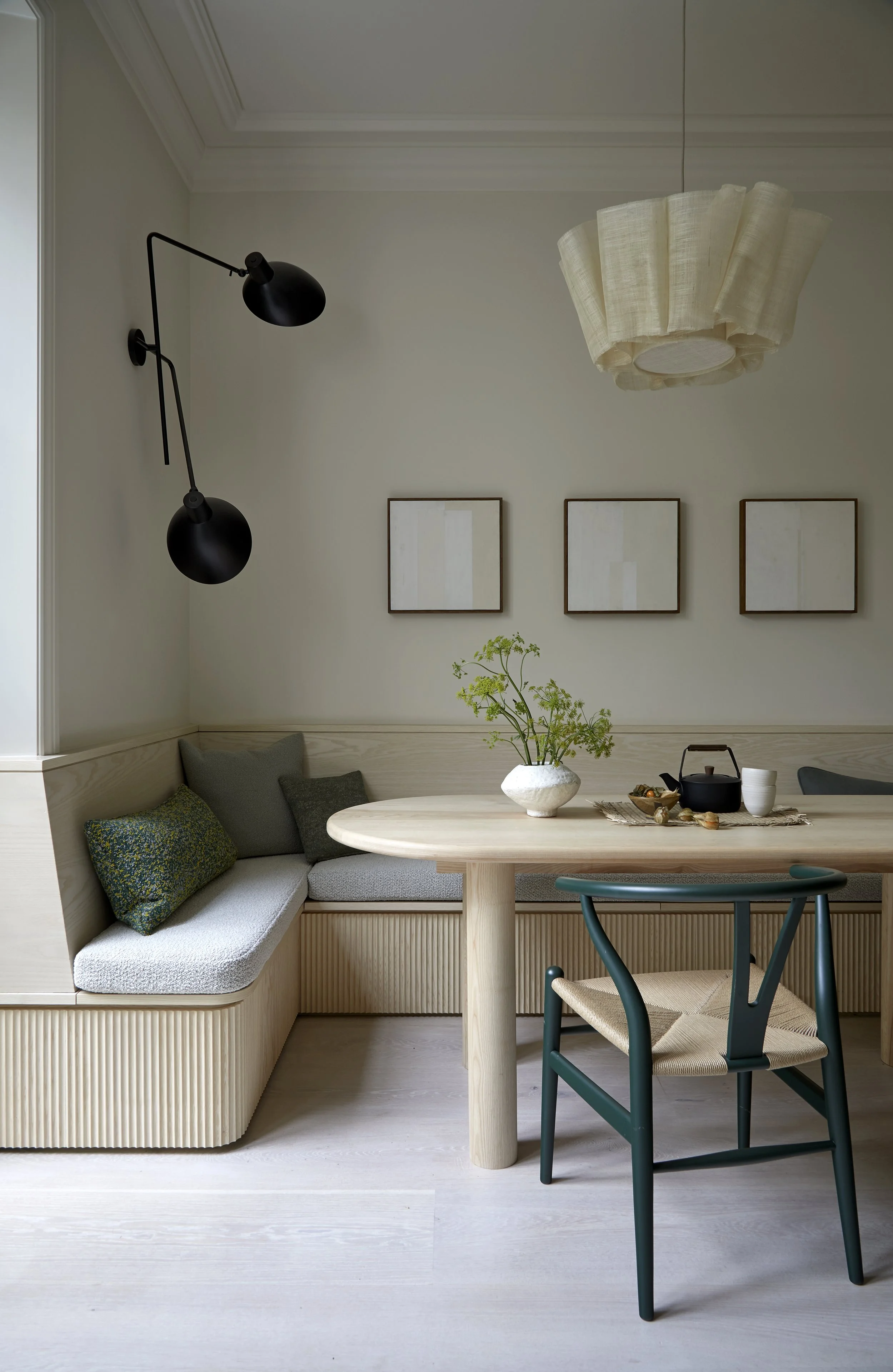Calm, neutral dining space with overhead and wall lighting