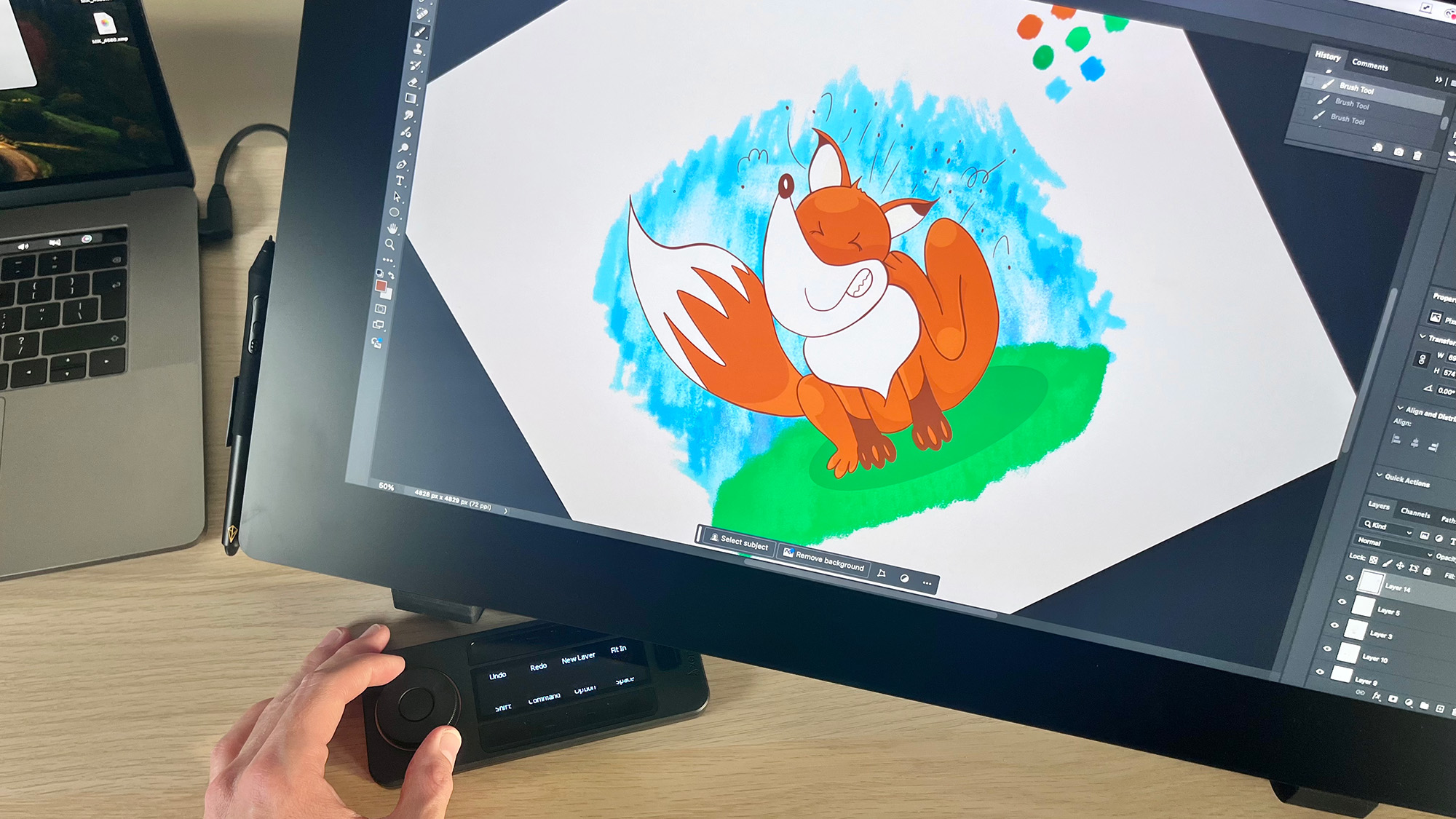 Hand using Quick Keys remote on Xencelabs Pen Display 24+ with image of cartoon fox on the screen