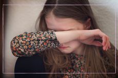 Little girl scared to go to school, covering her face