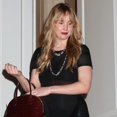 Actress Jennifer Lawrence attends an exclusive fashion event at the house of Lauren Santo Domingo, now owned by Ralph Lauren, in New York, looking chic in a black midi dress, burgundy handbag, and black pointed flats.