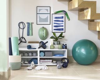 A home gym set up with equipment under the stairs in hallway
