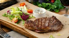 Wooden board with fillet steak and side salad