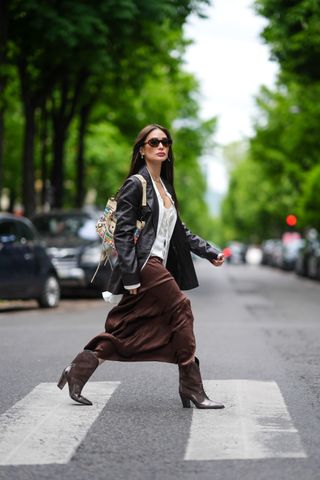 woman wearing leather jacket, skirt, and cowboy boots