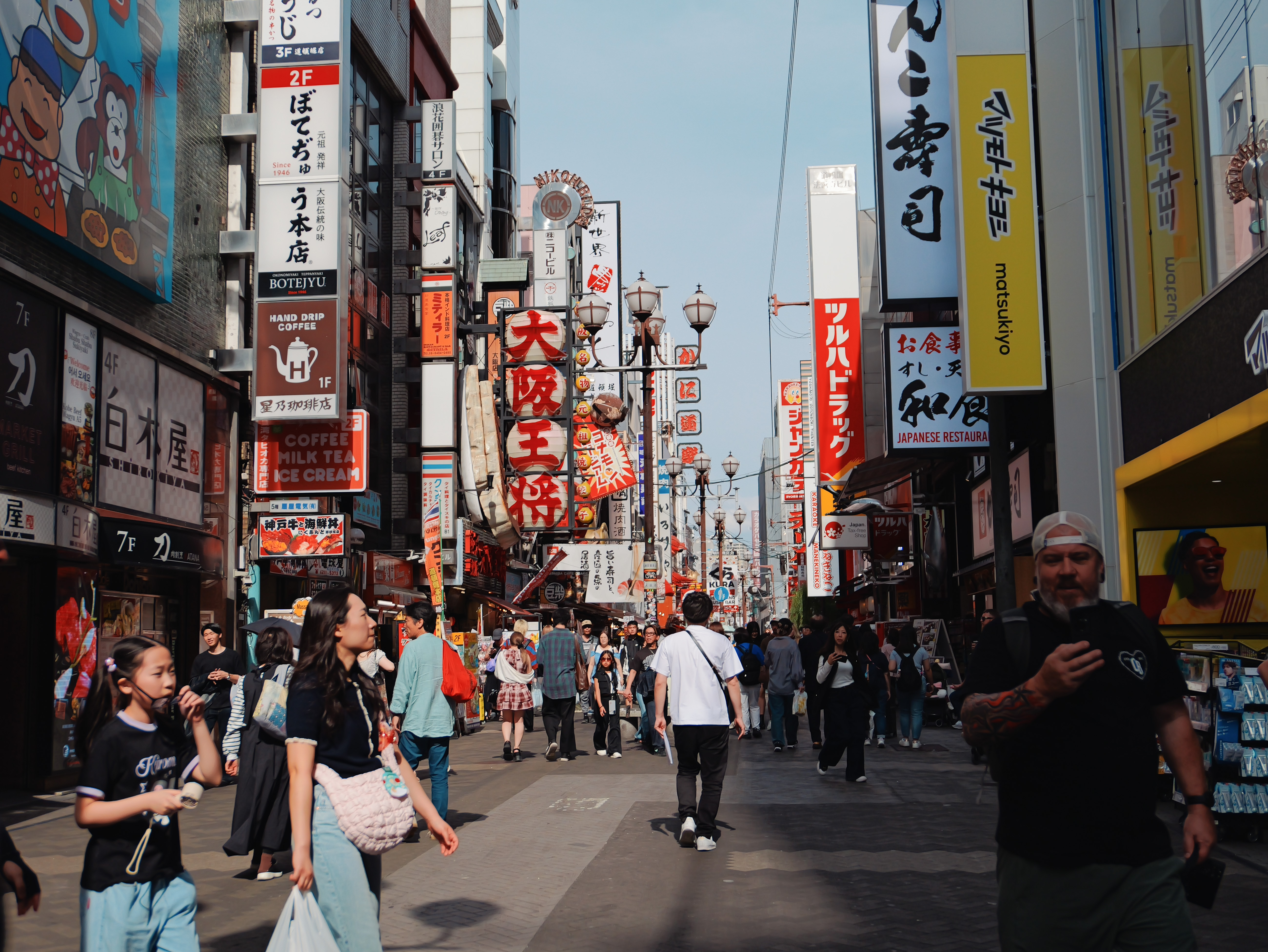 Crowded Osaka street lined with tall restaurant signs.