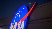 The crescent moon and Venus shine in the night sky above the NASA "Meatball" logo on the side of a building.