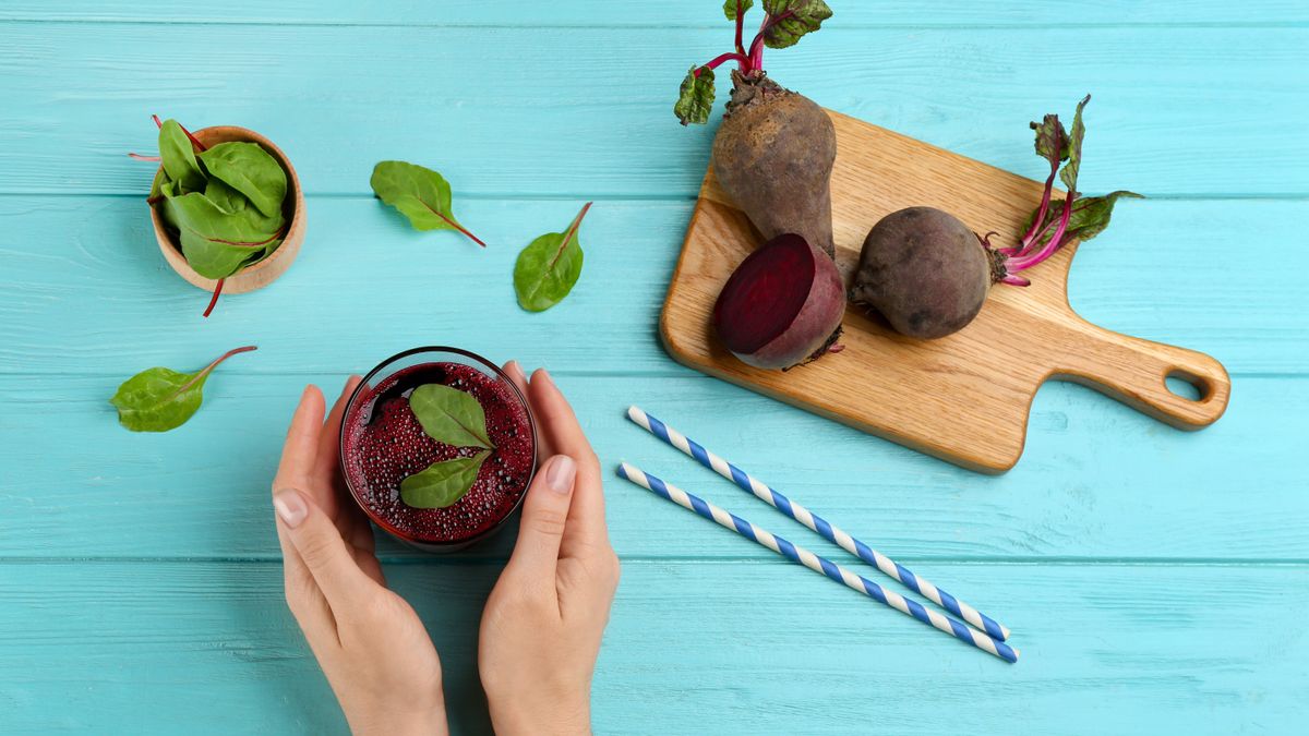 Woman preparing beetroot juice on a blue table