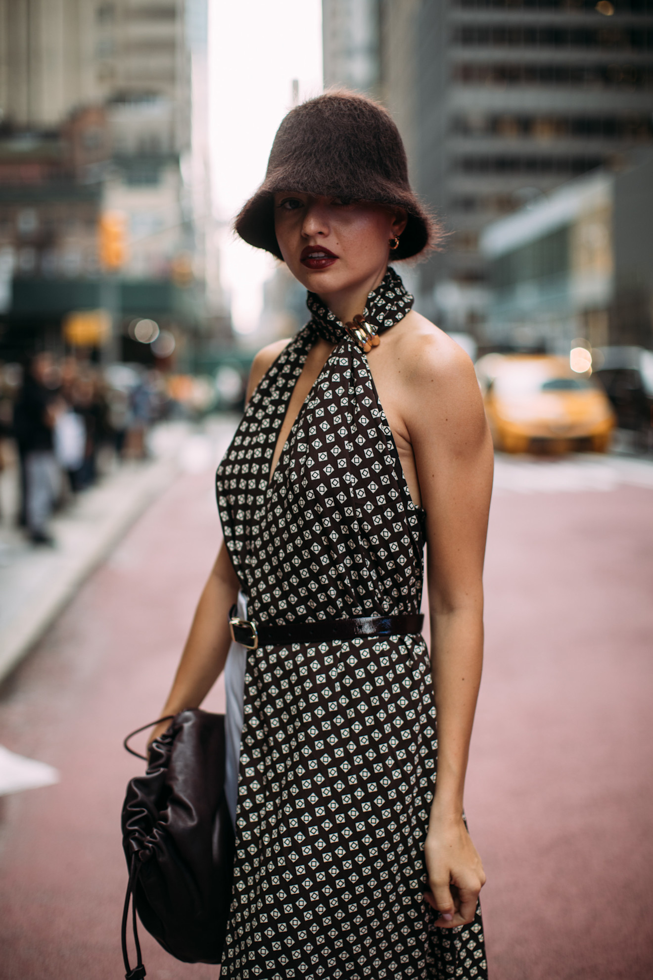 a woman with a brown bucket hat and dark red lipstick wearing a black and white dress during new york fashion week
