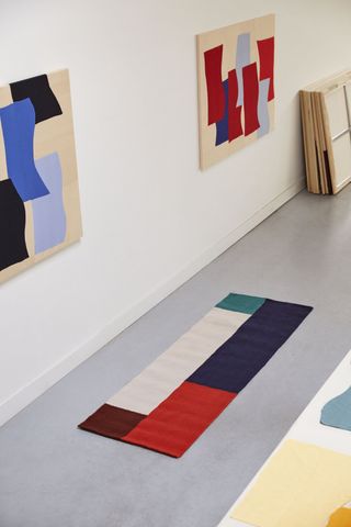 Colorful abstract rugs hanging on a wall, by Hay