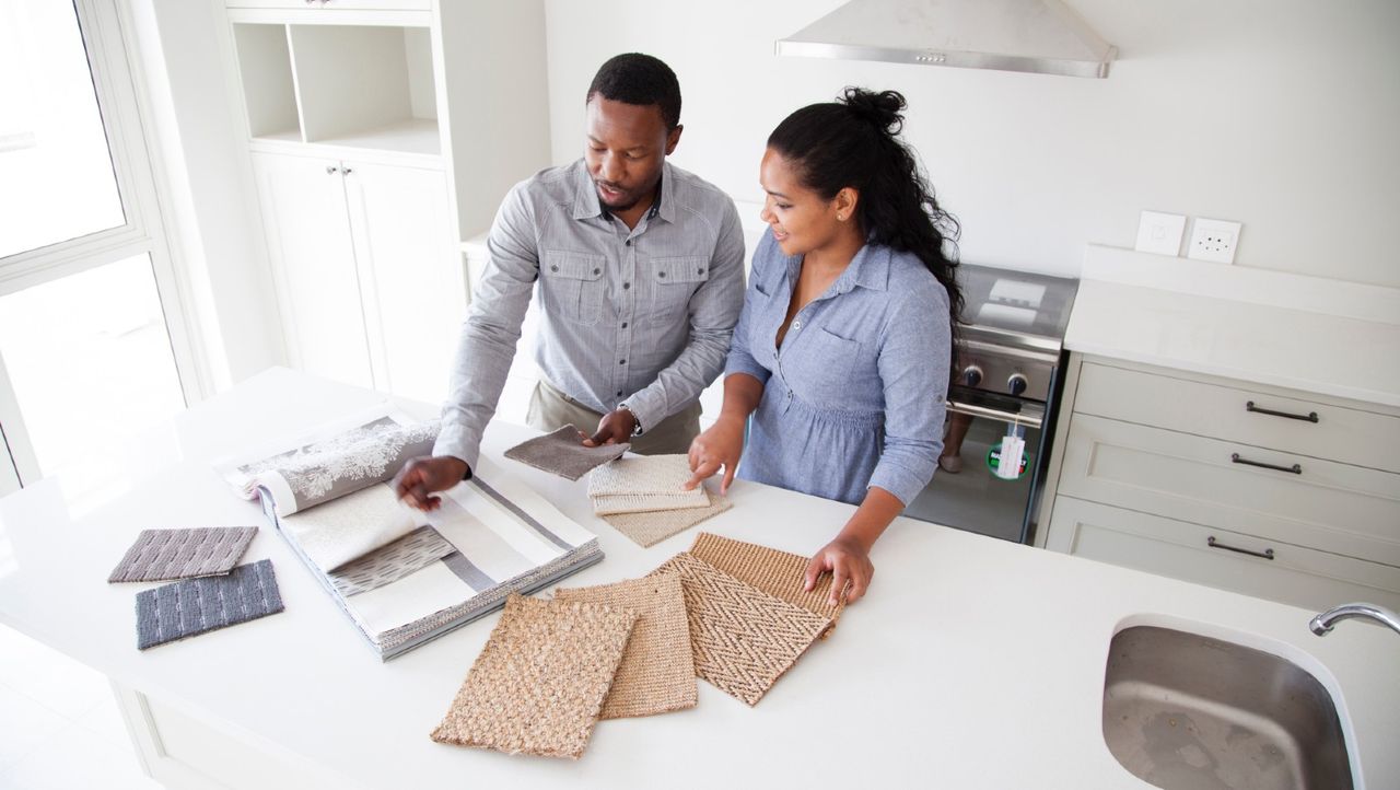 Couple examining fabric swatches in new home - stock photo home renovation