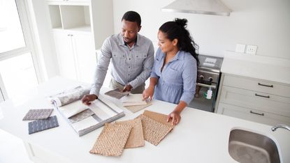Couple examining fabric swatches in new home - stock photo home renovation 