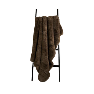 A brown faux fur throw draped across a ladder
