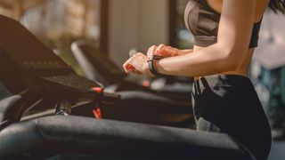 Image of woman looking at fitness tracker on wrist on treadmill