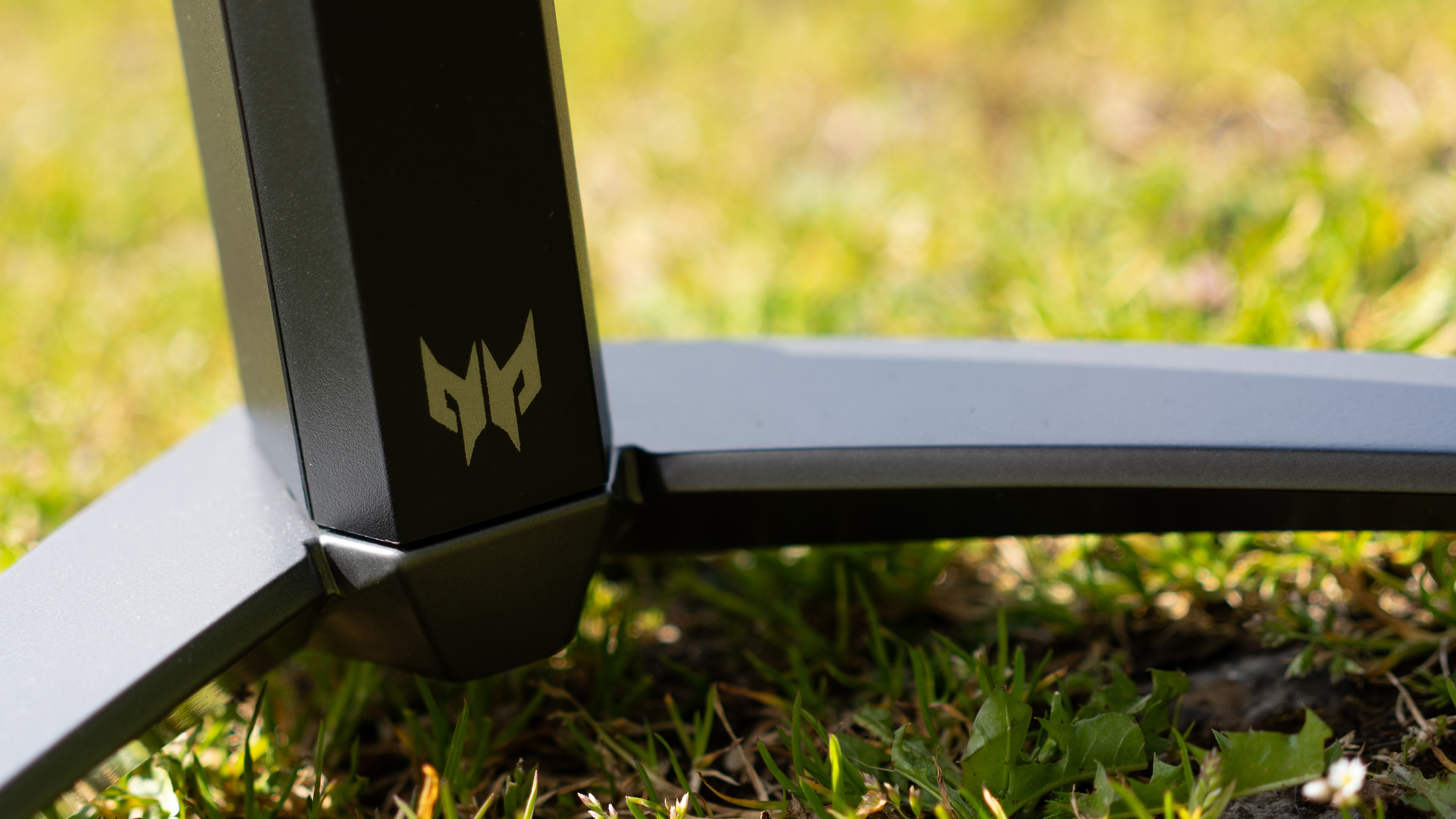 A black Acer Predator X27U monitor sitting on a sunny grass field