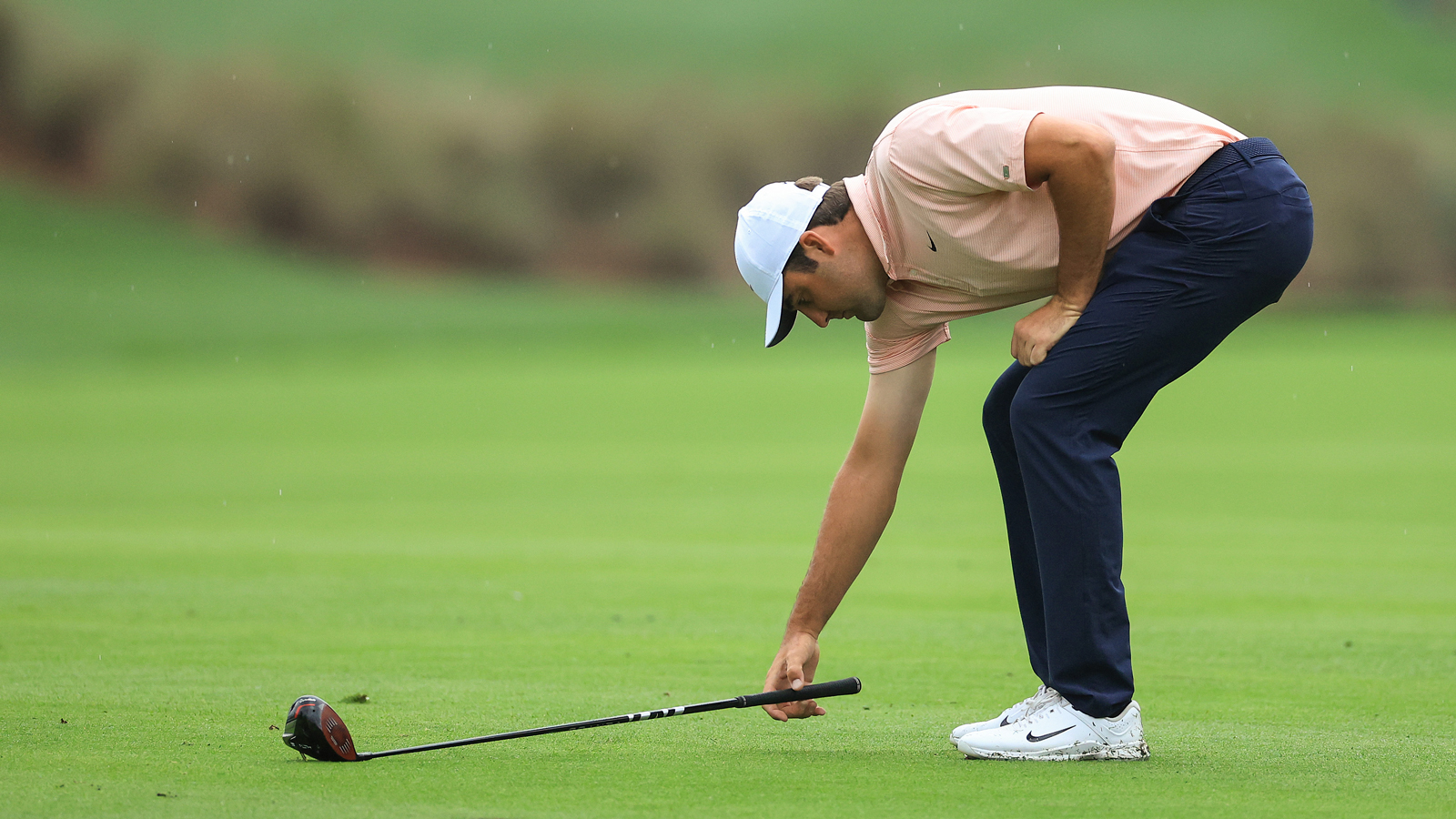 Scottie Scheffler lies a club down on the grass