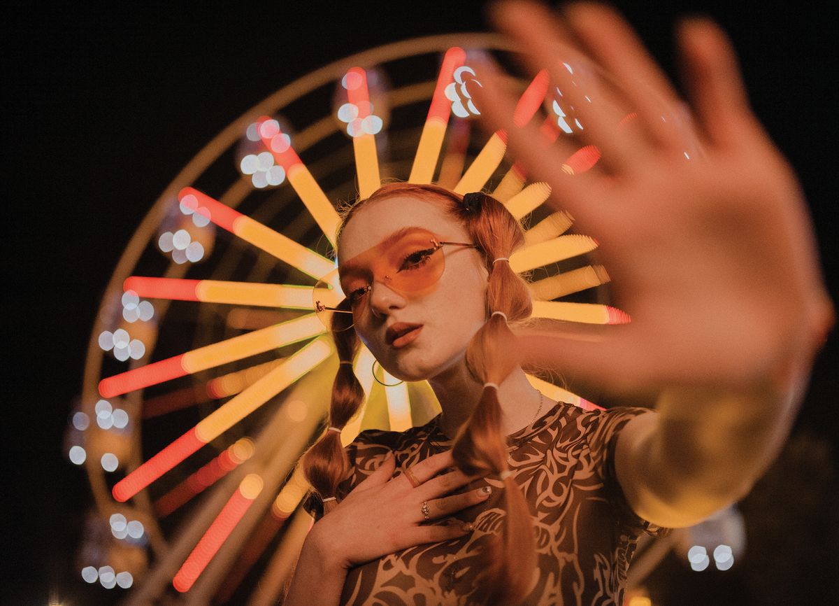 Woman standing in front of a ferris wheel at night