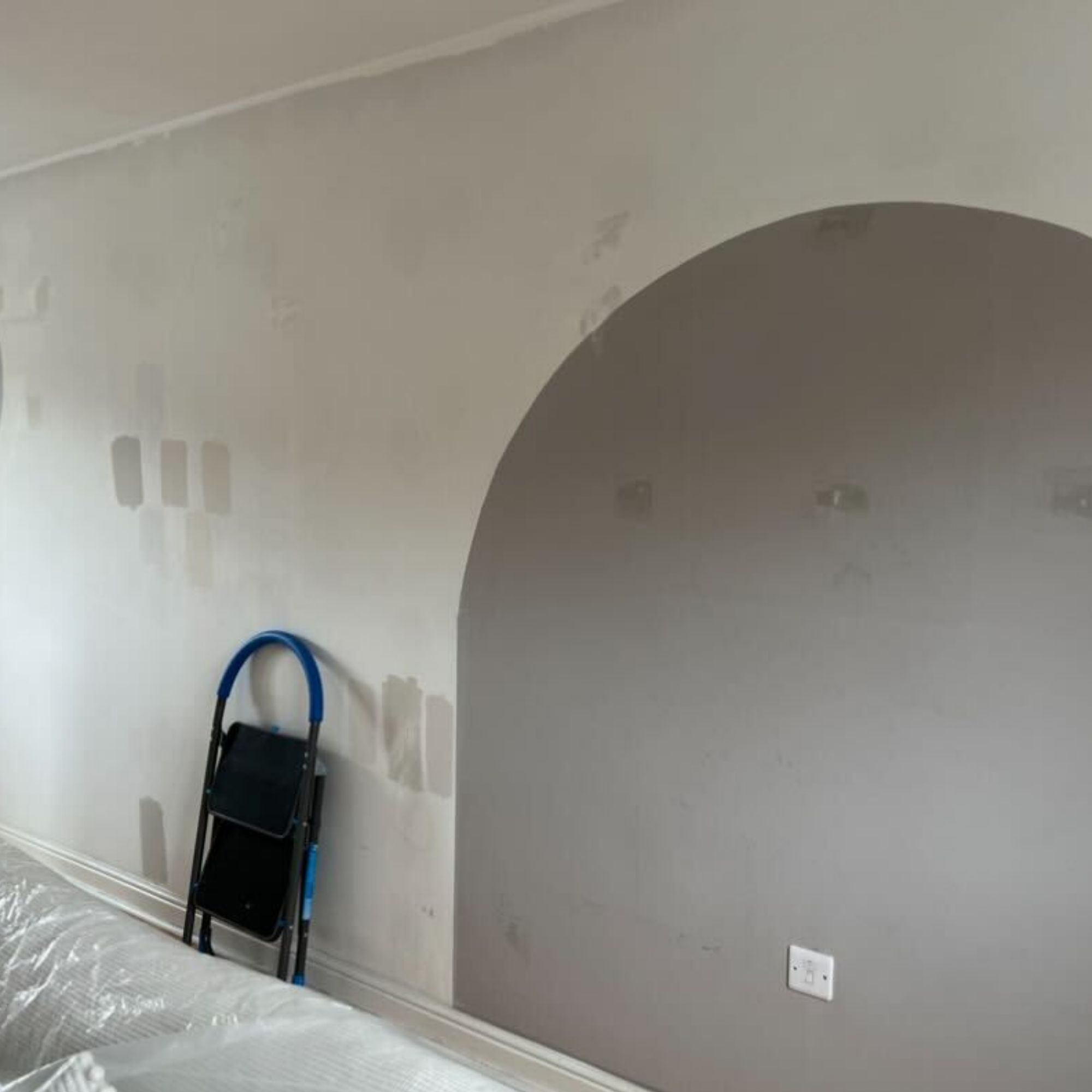 A white wall with a grey, painted arch, stained with candle smoke.