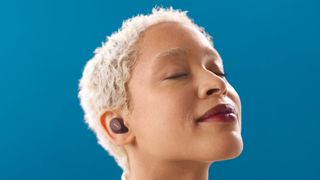 A woman on a blue background wearing the Jabra Elite 10 wireless earbuds