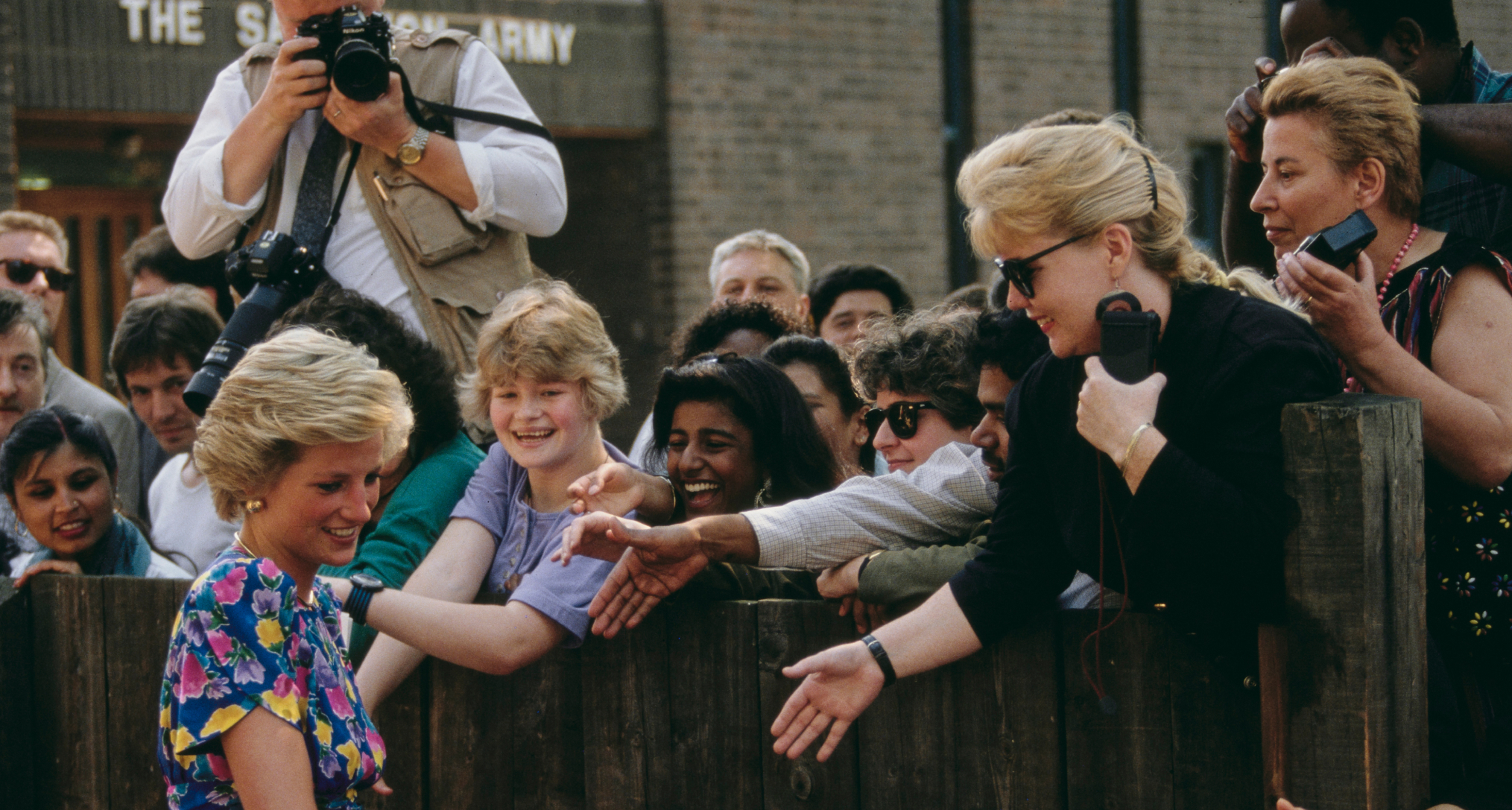 Princess Diana greeting fans leaning over a fence