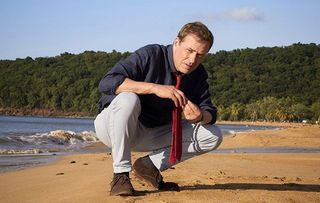 Star Ardal crouches on a beach in the new series of Death in Paradise