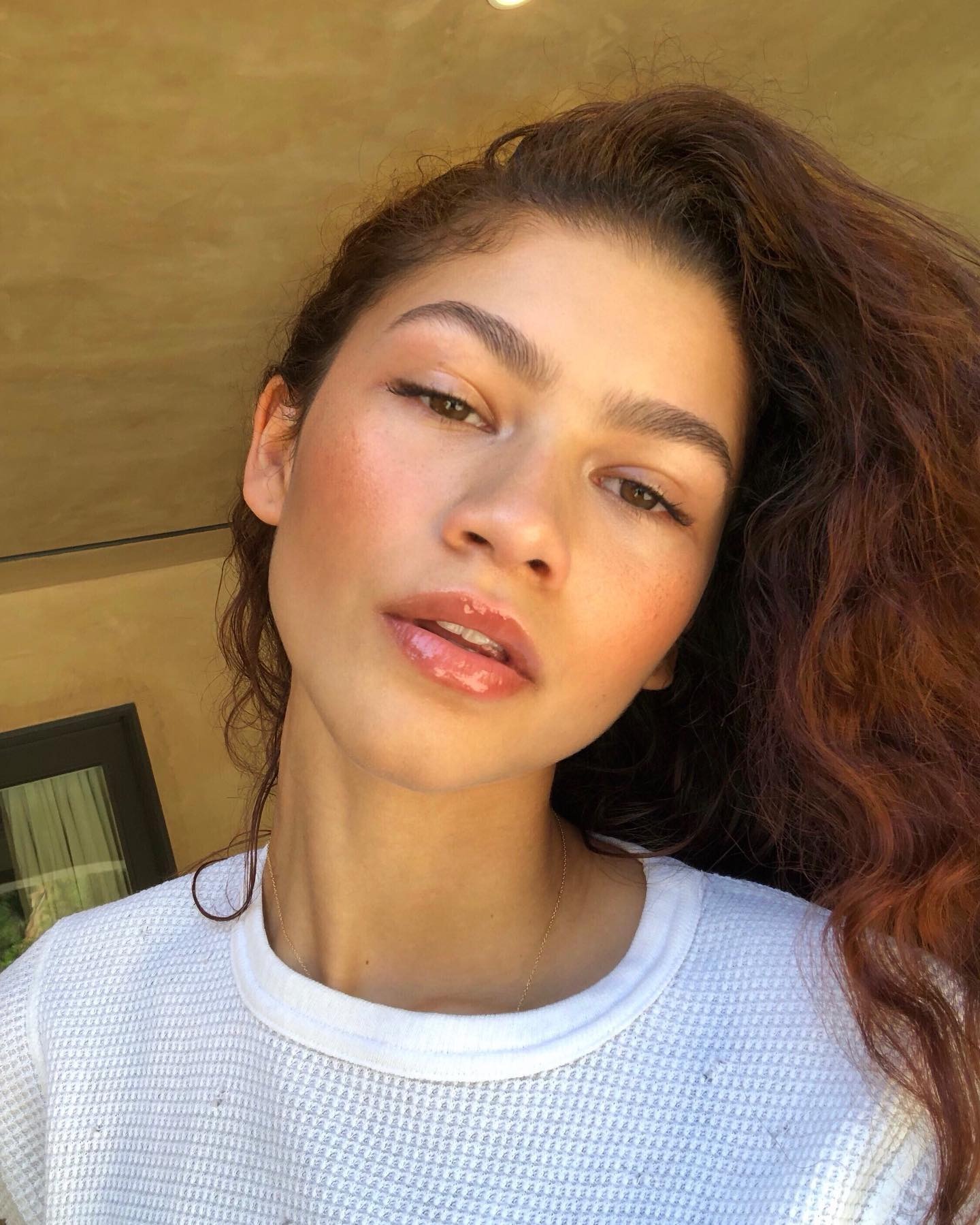 Zendaya taking a selfie with deep, cherry red hair