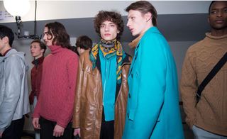 Several male models standing in studio with brightly coloured clothing