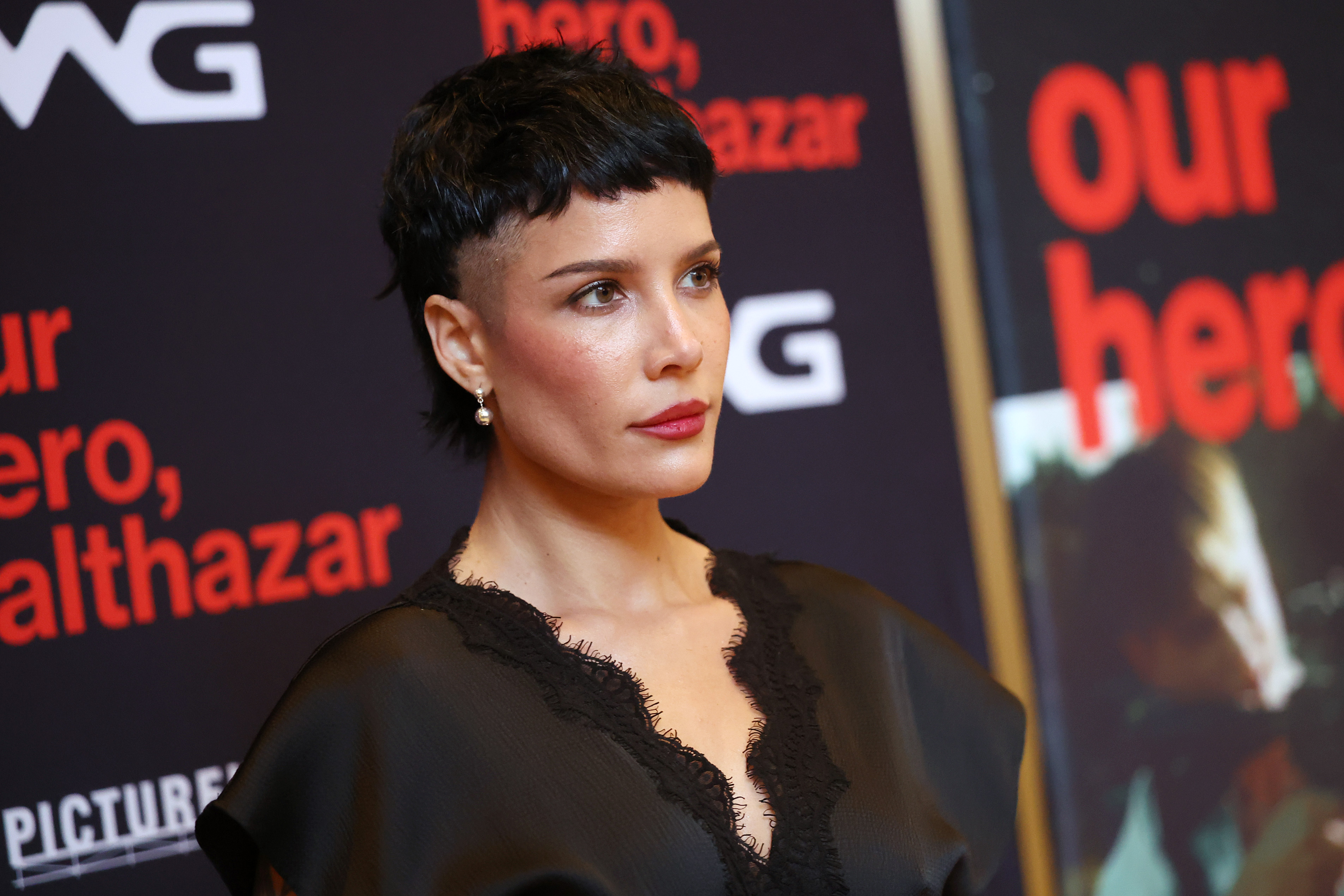 a woman with a short, dark haircut posing at a film screening