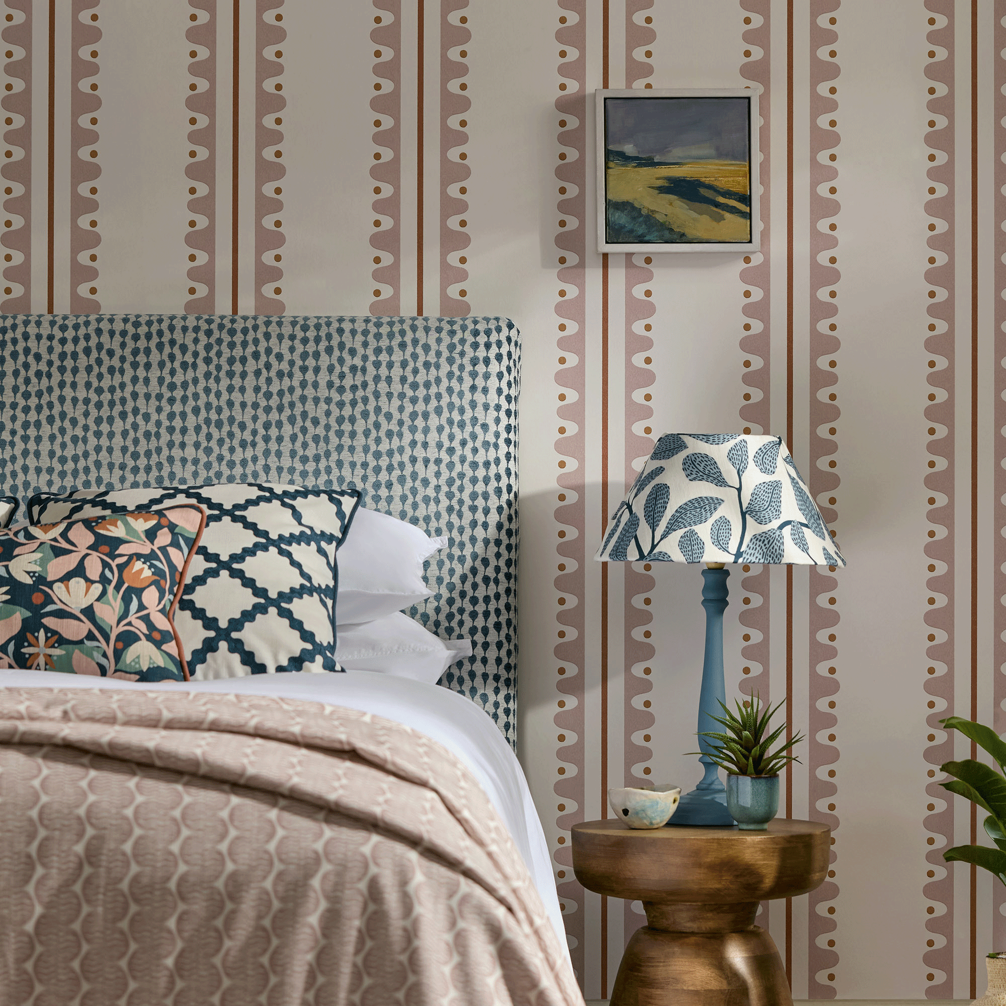 Blue headboard in bedroom with pink and white wallpaper