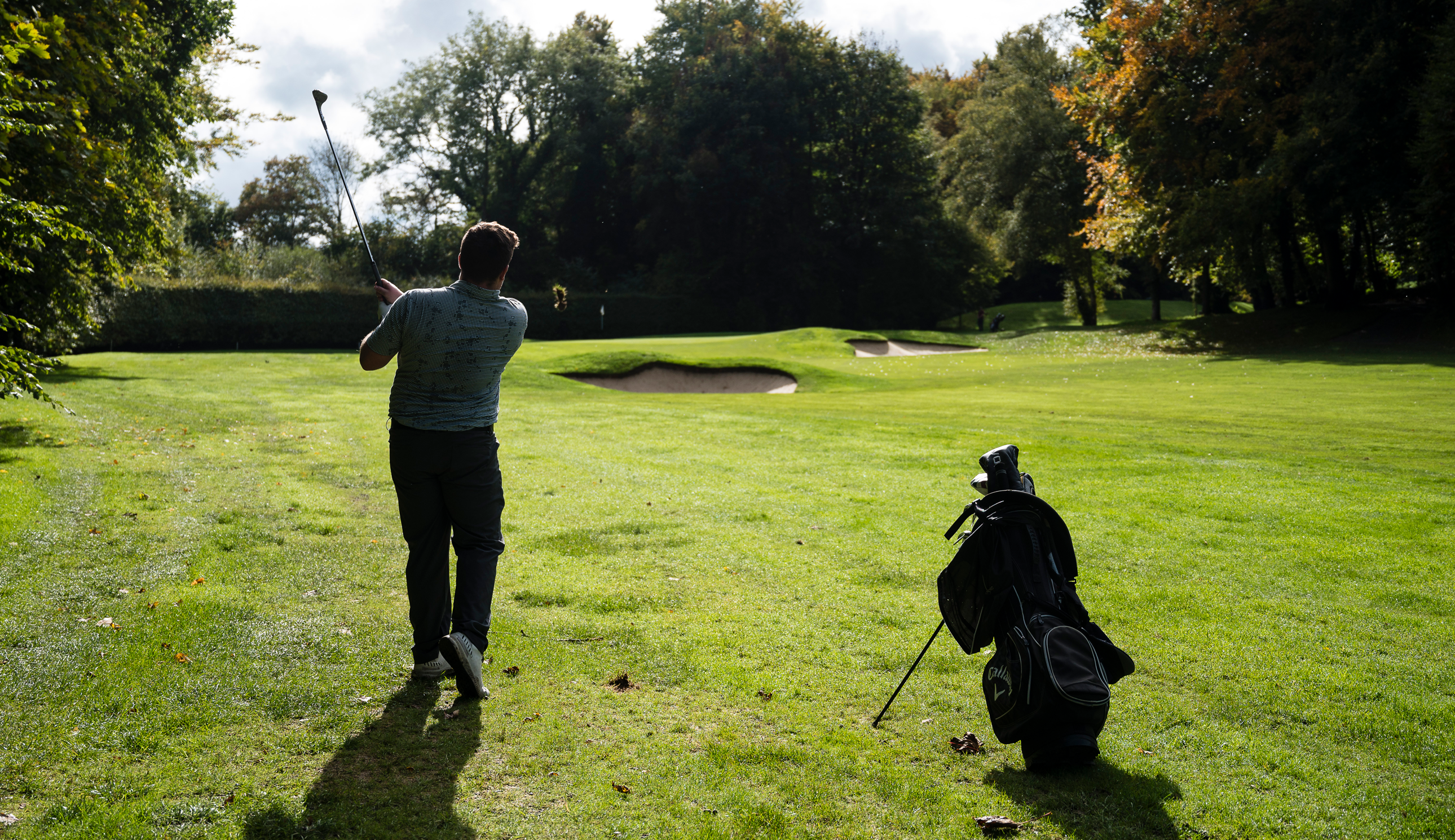 A golfer hits a wedge shot into a green
