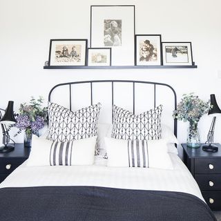 Bedroom with double bed, metal headboard, black side tables and pictures on the wall