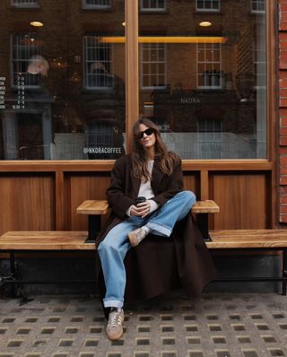 woman wearing cuffed denim outfit with brown long jacket