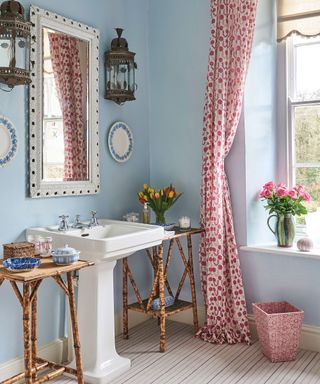 An example of how to make a small bathroom look bigger showing a blue bathroom with a pink curtain