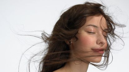 Woman with windswept brunette hair using the best blue shampoo for brunette hair