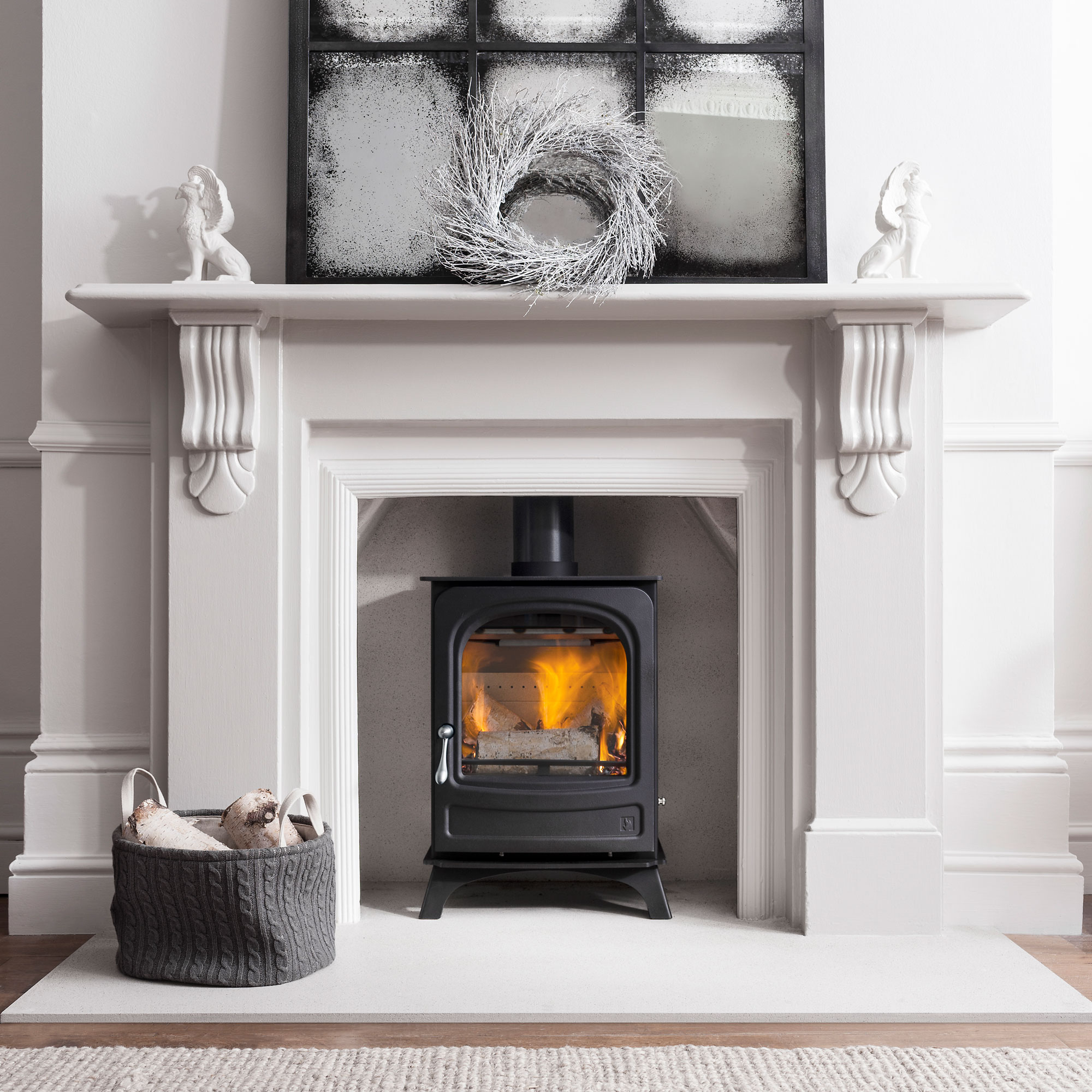 black cast iron log burning stove in white traditional fire surround