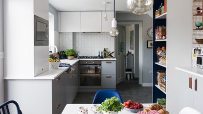 Georgia Broome kitchen: grey and white contemporary kitchen with monochrome pendant lights, white metro tile splashback and grey slate-effect floor